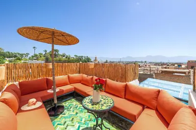 an orange couch with an umbrella on a patio at Riad Symba Exclusive with New Heated Pool and Breakfast Included in Marrakech