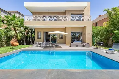a villa with a swimming pool in front of a house at Villa Narjisse , Élégance et Calme, piscine privée in Marrakech
