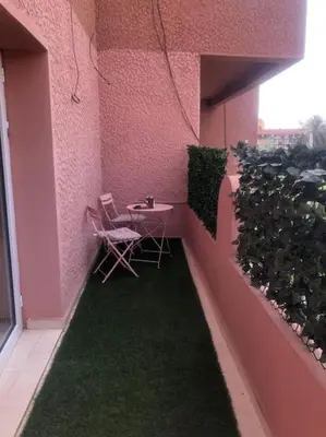a small patio with a table and chairs on a pink wall at Marrakech-Central location 2 Bdrm in Marrakech