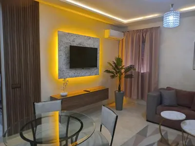 a living room with a glass table and a television at Luxury Apartment With Swiming Pool in Hivernage Marrakech in Marrakech