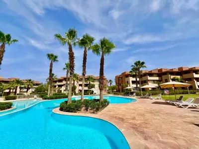 a swimming pool with palm trees in a resort at Prestigia Apart 29 in Marrakech