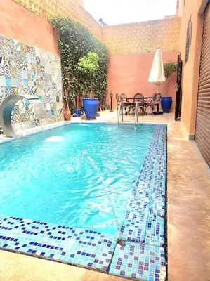 a swimming pool with blue tiles on the side of a building at Beautiful Central Marrakech Villa in Marrakech