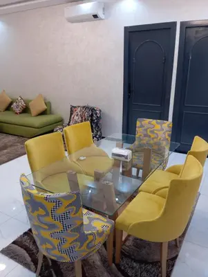 a living room with a glass table and yellow chairs at Marrakech -giliz in Marrakech