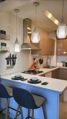 a kitchen with a stove and two chairs and lights at Nid douillet dans la ville Rose in Marrakech