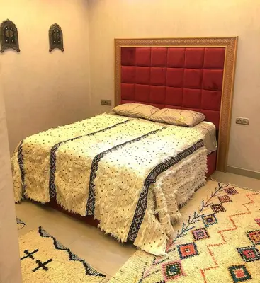 a bedroom with a bed with a red headboard and a rug at Nid douillet dans la ville Rose in Marrakech