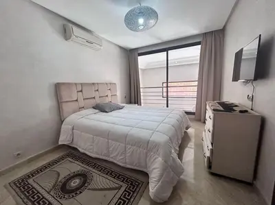 a bedroom with a large bed and a television at Appartement Duplex Haut Standing in Marrakech