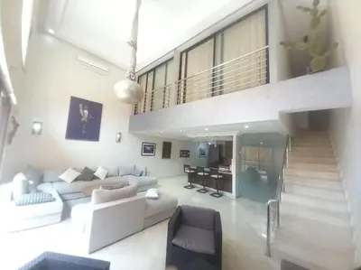 a living room with a couch and a staircase at Appartement Duplex Haut Standing in Marrakech