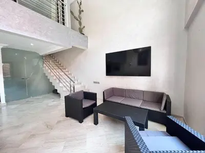 a living room with a couch and a tv on a wall at Appartement Duplex Haut Standing in Marrakech