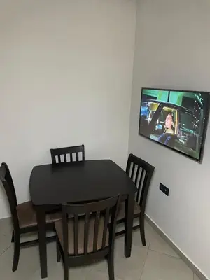 a dining room table and chairs with a tv on the wall at Stylisches City-Apartment im Herzen von Marrakech Gueliz in Marrakech