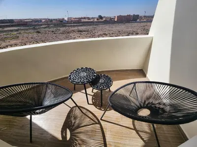 four chairs and tables on a balcony with a view of the beach at Residence Blida Gueliz 2 Chambres in Marrakech