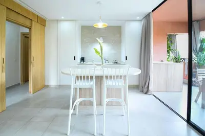 a kitchen with a white table and two white stools at Appartement luxe type Suite hôtel Hivernage in Marrakech