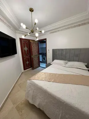 a bedroom with a large bed and a flat screen tv at Studio T2 vu sur piscine in Marrakech