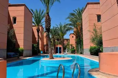 a swimming pool with palm trees in a resort at Al Qaria Assiyahia Riad Fadil 44 in Marrakech