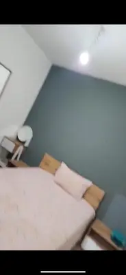 a room with a bed and a light blue wall at Basatin targa a giliz in Douar Moulay Hafid