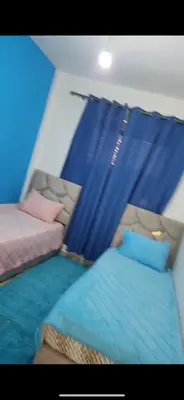 a bedroom with two beds and a blue curtain at Basatin targa a giliz in Douar Moulay Hafid