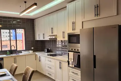 a kitchen with white cabinets and a stainless steel refrigerator at Luxury Condo in Downtown Hivernage Neighborhood in Marrakech