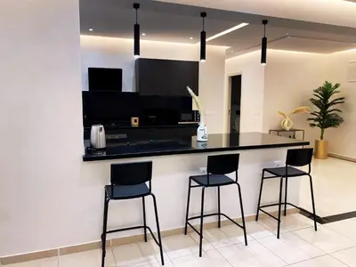 a kitchen with a black counter and three bar stools at Haut standing coeur Gueliz in Marrakech