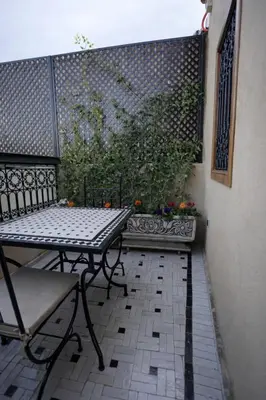a table and chair on a patio with a fence at Riad Palais MERYEM in Marrakech