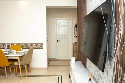 a living room with a tv and a table with chairs at Boho Haven Hivernage - Plein centre ville in Marrakech