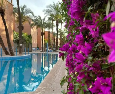 a bunch of purple flowers next to a swimming pool at RIAD Le shams in Marrakech