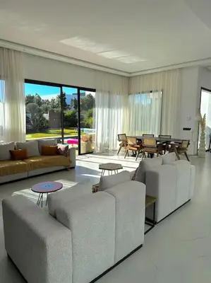 a living room with couches and a table and chairs at Villa Alanaé piscine chauffée in Douar Bellouk