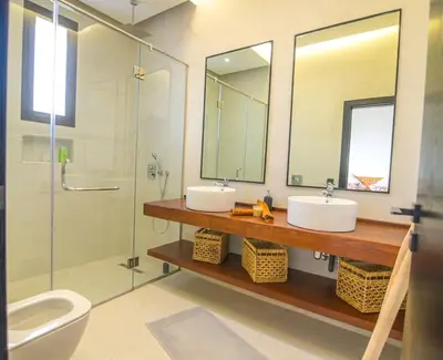 a bathroom with two sinks and a glass shower at Villa Alanaé piscine chauffée in Douar Bellouk