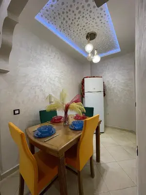a dining room with a wooden table and yellow chairs at COZY Appartement in Marrakech