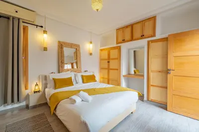 a bedroom with a large white bed with yellow pillows at Riad SWAN-exclusif - Piscine chauffée - Petit déjeuner in Marrakech