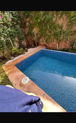 a blue swimming pool with a white object next to it at Petite villa cosy et agréable avec jacuzzi privé in Marrakech
