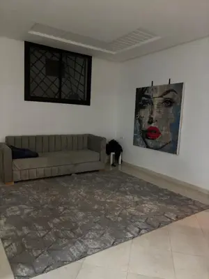 a living room with a couch and a painting on the wall at Petite villa cosy et agréable avec jacuzzi privé in Marrakech