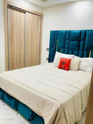 a large bed with a blue headboard and a red pillow at Magnifique appartement à Marrakech in Marrakech
