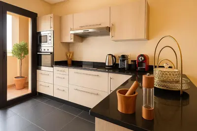 a kitchen with white cabinets and a black counter top at Luxurious M avenue Hivernage - next to Pestana CR7 in Marrakech