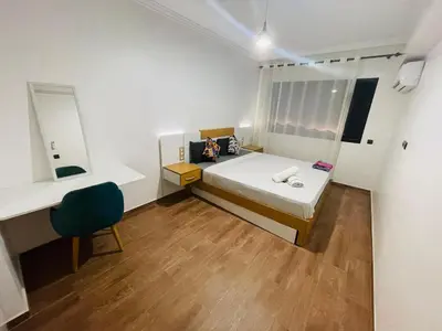 a bedroom with a bed and a desk and a chair at Super appartement in Marrakech