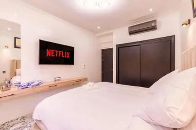 a white bedroom with a bed and a television at Oasis exclusive avec piscine dans le centre-ville in Marrakech