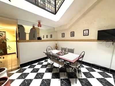 a dining room with a table and a checkered floor at Riad Dilia in Marrakech