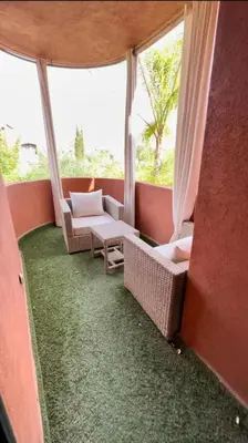 a balcony with two chairs and a table and windows at Charmant villa au cœur de la palmeraie in Douar Caïd Layadi