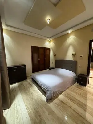 a bedroom with a white bed and a wooden floor at Charmant villa au cœur de la palmeraie in Douar Caïd Layadi