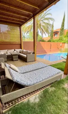 a patio with a bed and a couch and a pool at Charmant villa au cœur de la palmeraie in Douar Caïd Layadi