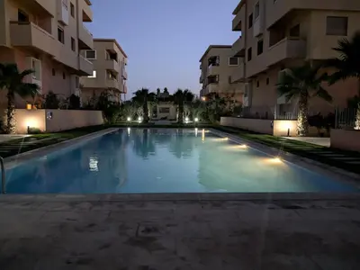 an empty swimming pool in front of apartment buildings at night at Janat House in Marrakech