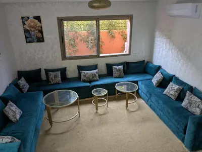 a living room with a blue couch and two tables at Janat House in Marrakech