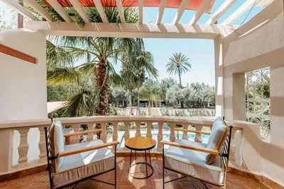 a balcony with chairs and a table and palm trees at La Villa d'Oz pour 12 personnes Golf Amelkis in Marrakech