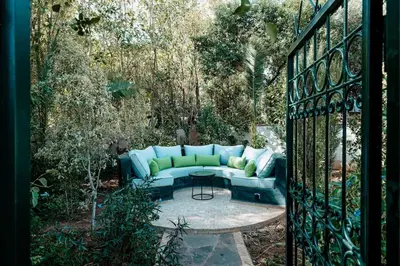 a blue couch sitting in a garden behind a gate at La Villa d'Oz pour 12 personnes Golf Amelkis in Marrakech