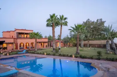 a house with a large swimming pool with palm trees at Villa 5 suits with pool and montains view in Sraghna