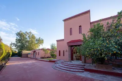 a pink building with a tree in front of it at Villa 5 suits with pool and montains view in Sraghna