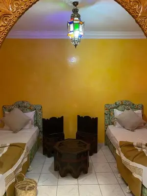 a room with two beds and a chandelier and a table at Riad Tichka piscine palmeraie in Marrakech