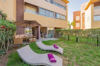 a house with purple slippers on the grass next to a building at Relax Front of Pool - Golf- Fiber Optic in Marrakech