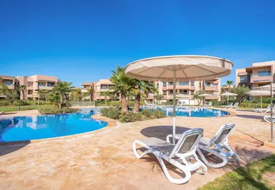 a swimming pool with two chairs and an umbrella at Relax Front of Pool - Golf- Fiber Optic in Marrakech