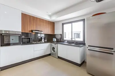 a kitchen with white cabinets and a washer at New! Appt Spacieux et Lumineux à Menara Garden in Marrakech