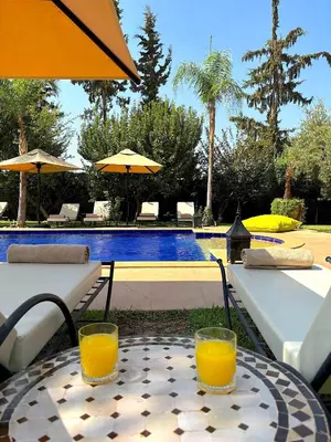 two glasses of orange juice sitting on a table near a pool at Palais Ona in Marrakech