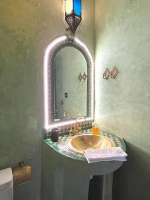 a bathroom with a sink with a lighted mirror at Palais Ona in Marrakech